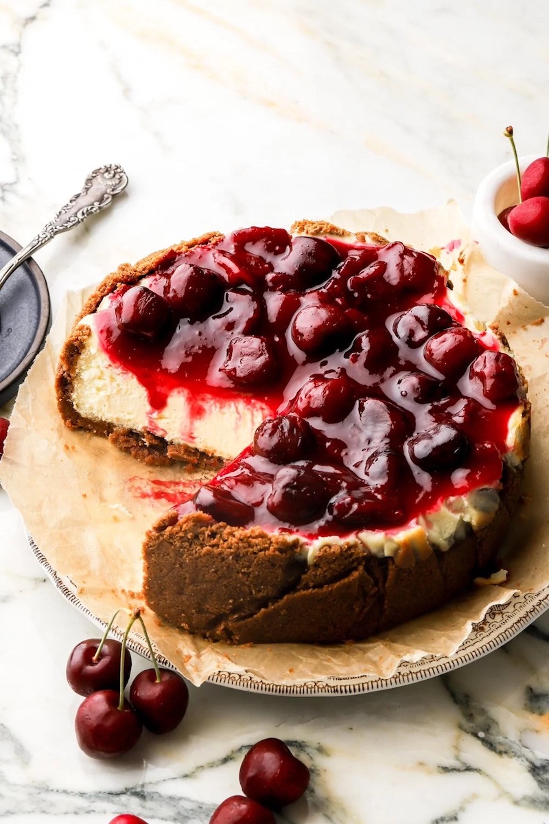 Smooth vanilla cheesecake with cherry pie filling on top.