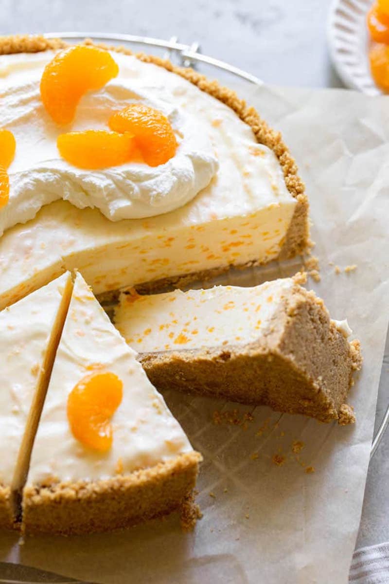 A no‑bake orange creamsicle cheesecake with a graham cracker crust, topped with whipped cream and mandarin orange segments.